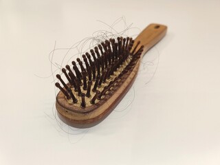 A dirty comb that a lot of hair falls out. The photo was taken up close against a white background.