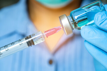 doctor's hand holds a syringe and a blue vaccine bottle at the hospital. Health and medical...