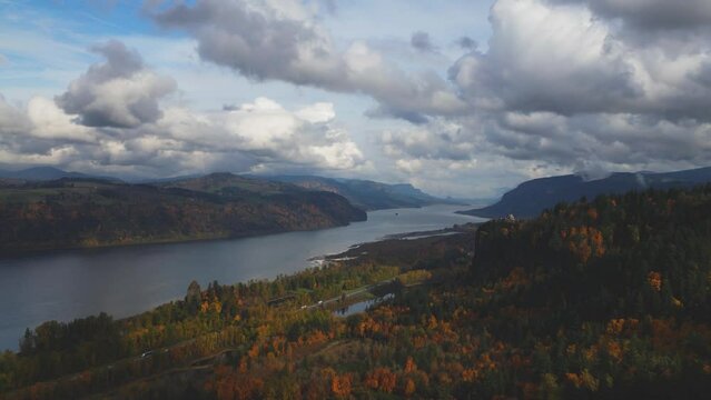 Drone shot of the Columbia River Gorge in Oregon during a dramatic cloudy sky in the fall showing nearby traffic on road.
