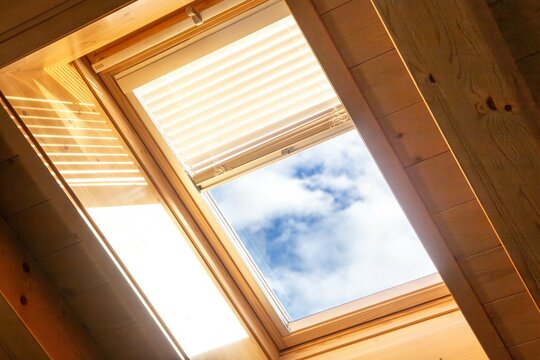 Innenaufnahme von einem Dachfenster mit elektronischer Jalousie an einer Decke mit Holzverkleidung