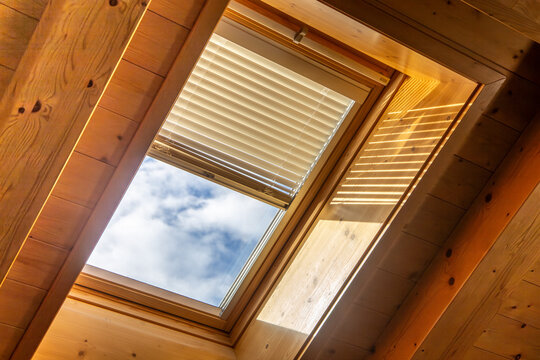 Innenaufnahme von einem Dachfenster mit elektronischer Jalousie an einer Decke mit Holzverkleidung