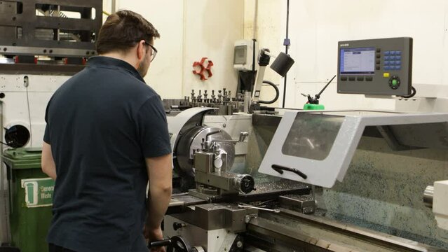 Factory worker operating CNC milling machine with, side view