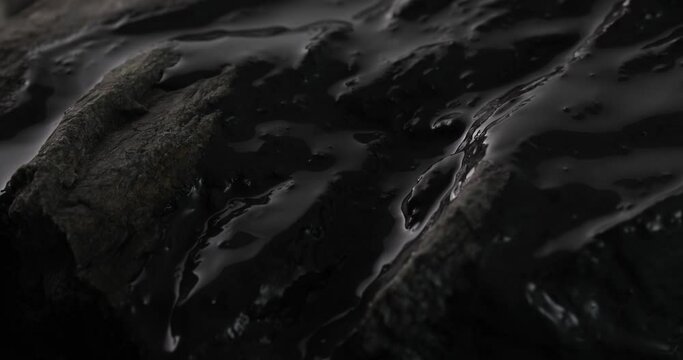 Glossy Oil Coating on Rocky Shore. Close-up, shallow dof.