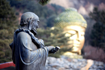 View of the monk statue against the golden Buddha statue