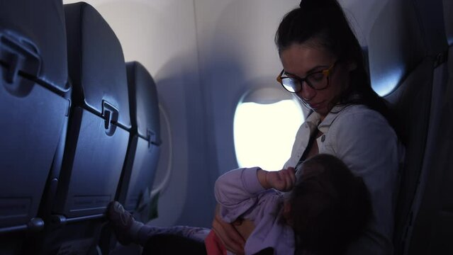 Mother holding fussy baby on airplane - single parent traveling