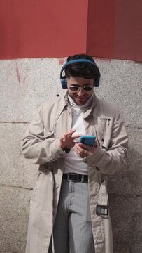 Stylish colombian young man using phone to listen to music and dance.