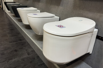 Ceramic toilet bowls of different types on a shop window. Sale of sanitary equipment in a specialized store.