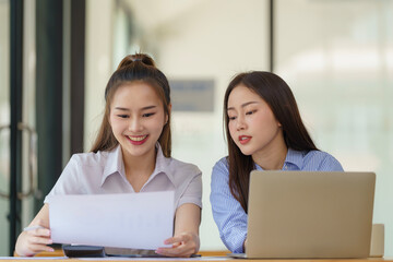 Two Asian businesswomen discuss new startup project idea presentation and analyze planning and financial statistics and investment market at the office.