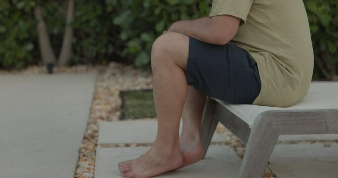 Man sitting by swimming pool with clothes on not going in - afraid of water