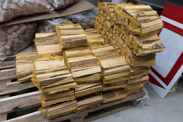 Firewood lying on a pallet for a fireplace folded in yellow grids. Close up.