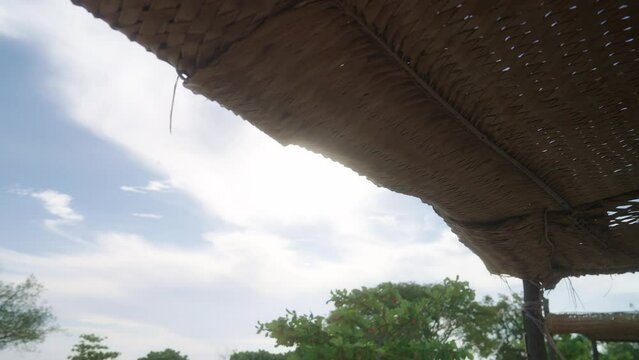 Exotic destination hut with thatched roof in low angle towards sun