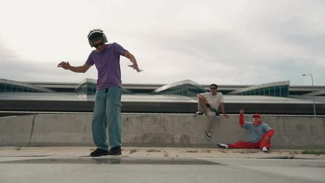Group of asian break dancer perform street dance with multicultural friend support and moving hip hop music. Attractive handsome hipster practice b boy dance at street. Outdoor sport 2024. Sprightly.