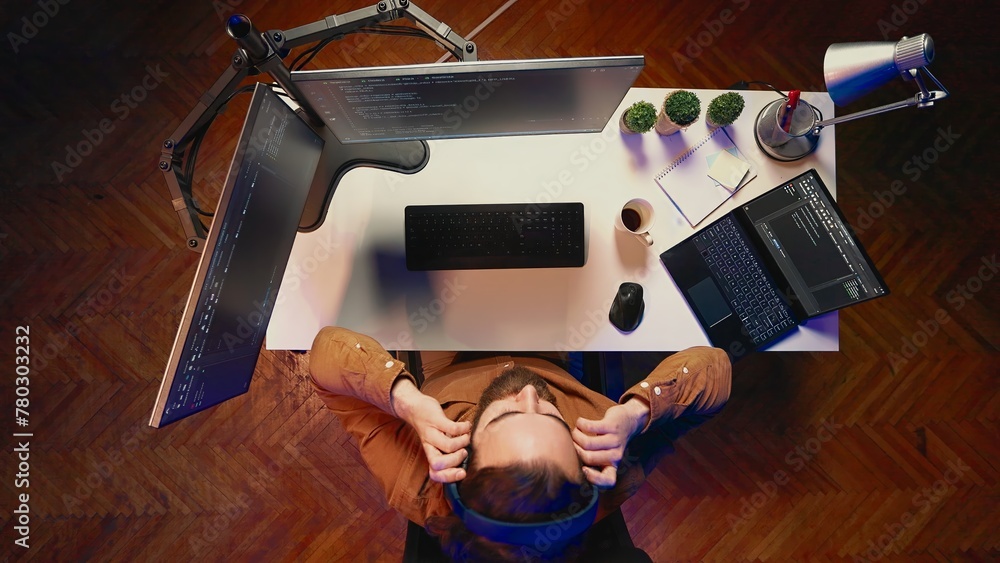 Poster top down view of technician puts headphones on while fortifying firewalls, teleworking for it compan
