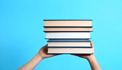 A hand holds a stack of books against a blue background.