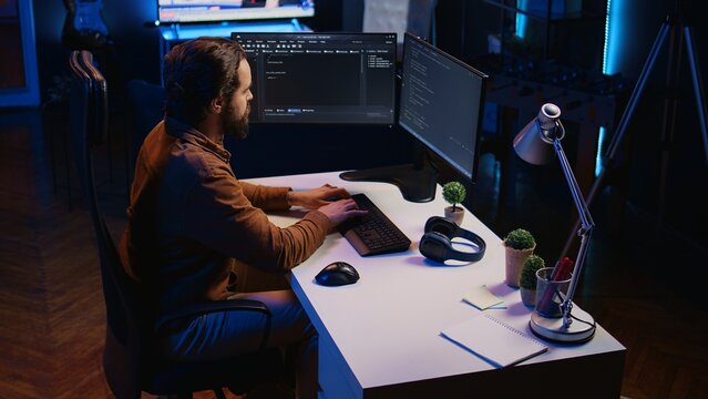 Computer scientist developing code on PC while in apartment office using java programming languages. IT admin brainstorming ways of fixing database errors while working from home, camera B