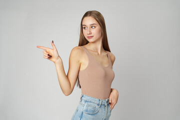 Young Woman in Tank Top Pointing at Something on gray background