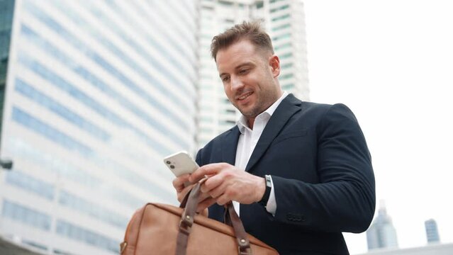 Caucasian business man checking mobile phone and looking report sales from marketing team while standing at urban city. Skilled manager working on mobile phone and looking at data analysis. Urbane.