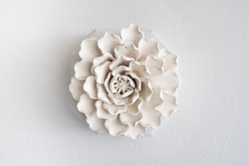 Elegant white ceramic flower sculpture mounted on a wall providing a minimalist and artistic decor element for modern interior