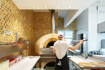 Chef Baking Pizza in a Traditional Wood-Fired Oven at an Italian Restaurant