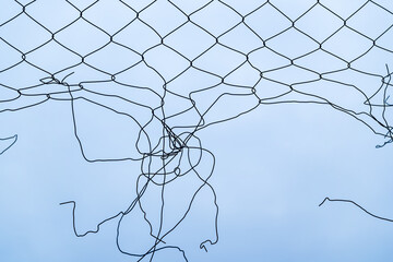 Broken torn chain link fence against overcast winter sky, concept of freedom