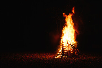 Bonfire burning at night, bright orange flames of fire, selective focus