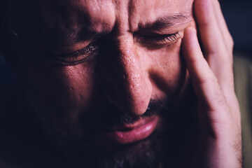 Hopelessness and despair, closeup of portrait of sad crying adult man grieving in dark room - obrazy, fototapety, plakaty