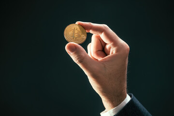 Cryptocurrency trader holding Bitcoin coin in hand
