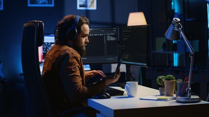 Developer focused on typing complex code in neon lit home office, listening music and developing...