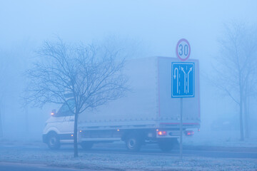 Traffic in fog, road signs and truck on the highway
