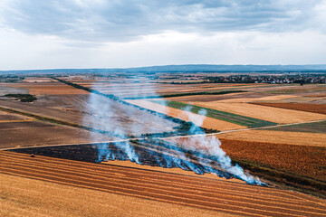 Wheat field stubble burning after the harvesting of grains is one of the major causes of air pollution, aerial shot from drone pov
