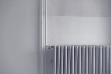 Old white heating radiator against white wall