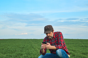 Smart farming, farm worker using smartphone in cultivated wheat field