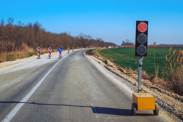 Traffic light signalization during road maintenance, red stoplight for traffic regulation