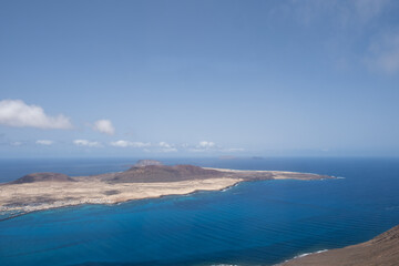Views of the island of La Graciosa from the viewpoint of El Rio. Turquoise ocean. Blue sky with big white clouds. Caleta de Sebo. Town. volcanoes. Lanzarote, Canary Islands, Spain