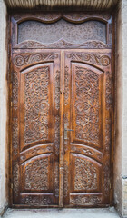 An ancient wooden door with patterns and ornaments in the ancient city of Khiva in Uzbekistan, wood carving