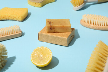 Sponges, brushes, lemon and bar of soap on blue background, close up
