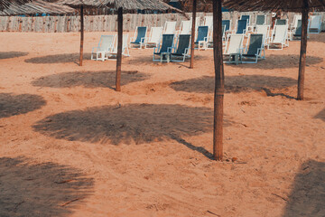 Reed straw sun umbrellas and deck chairs on sandy beach - 780313867