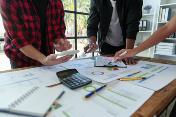 Teamwork process The Business team uses a calculator to calculate figures, business statistics, profit, cost analysis, and growth rate graph documents. data charts on the desk.
