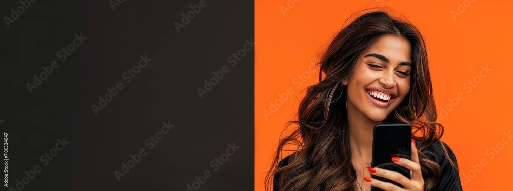 Wall mural photo of an elegant young woman in her 20s with long wavy hair, happy smiling while using an mobile 