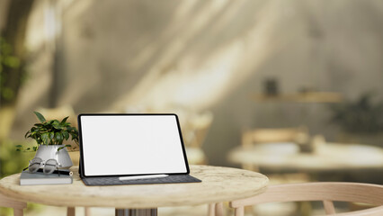 A white-screen digital tablet mockup is placed on a table in a cafe on a sunny day.