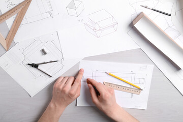 Man creating packaging design at light wooden table, top view