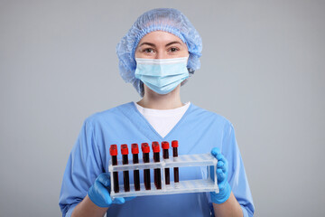 Laboratory testing. Doctor with blood samples in tubes on light grey background