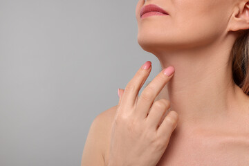 Fototapeta na wymiar Woman touching her neck on grey background, closeup. Space for text