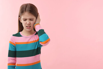 Hearing problem. Little girl suffering from ear pain on pink background, space for text