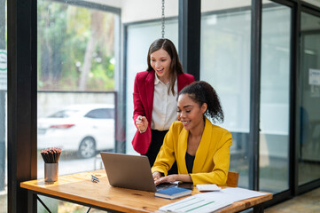 A businesswoman in a yellow blazer engaging in a productive discussion with a colleague in a red...