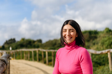 Portrait of smiling young woman wearing pink pullover in the park