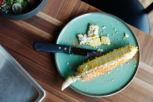 A plate of elote cut from cob with knife