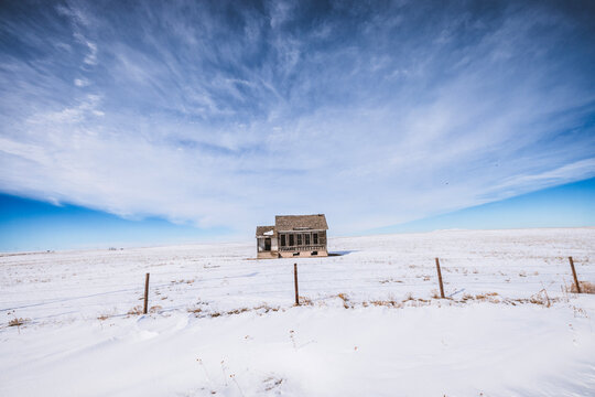 deserted dilapidated house stands alone on Nebraska prairie in winter