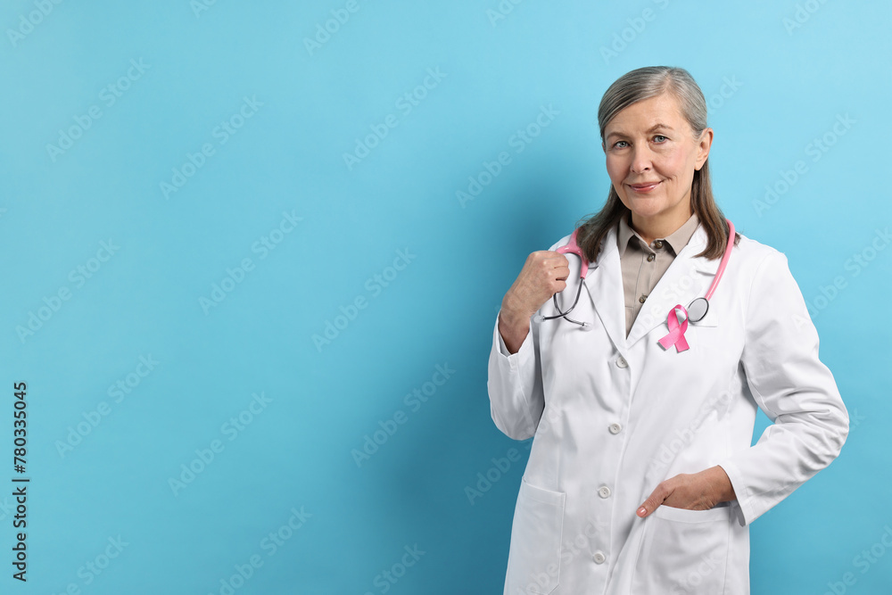 Wall mural Mammologist with pink ribbon on light blue background, space for text. Breast cancer awareness