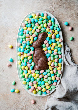 Overhead of chocolate bunny in tray of mini chocolate Easter eggs.